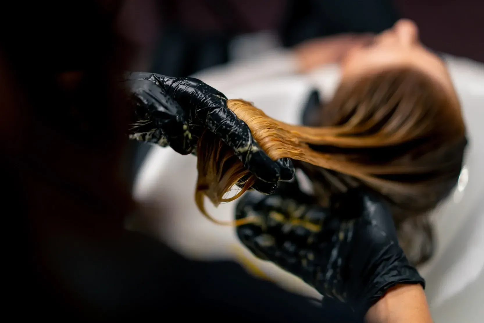 Coiffeuse appliquant une coloration sur les cheveux d'une cliente